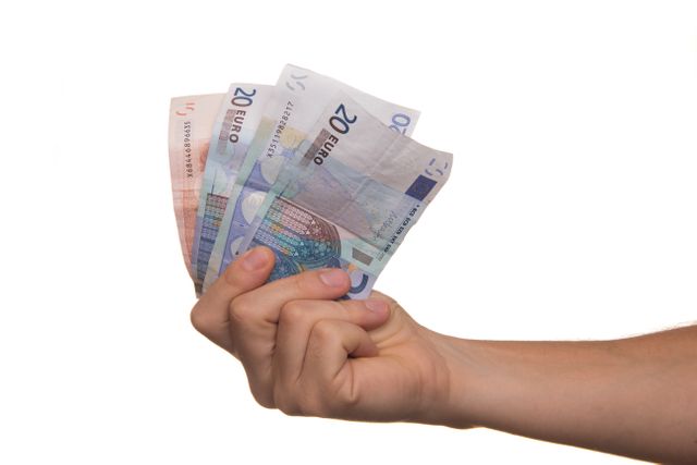 Hand holding multiple 20 euro bills against white background. Finance, economy and currency concept