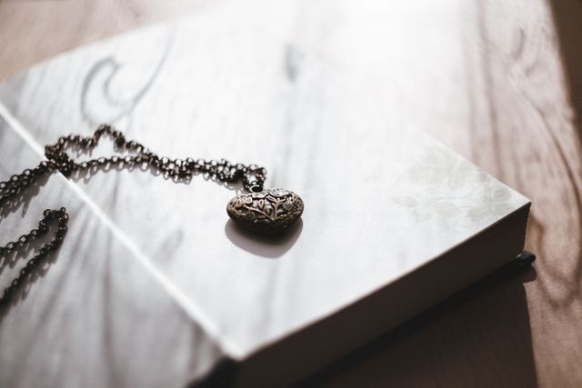 a heart shaped necklace on a book - Download Free Stock Photos Pikwizard.com