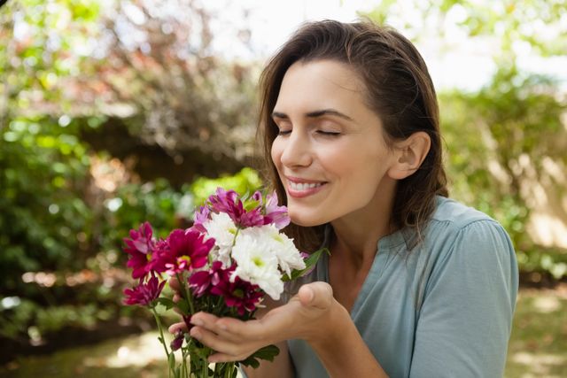 Smiling beautiful woman with eyes closed smelling flowers - Download Free Stock Photos Pikwizard.com