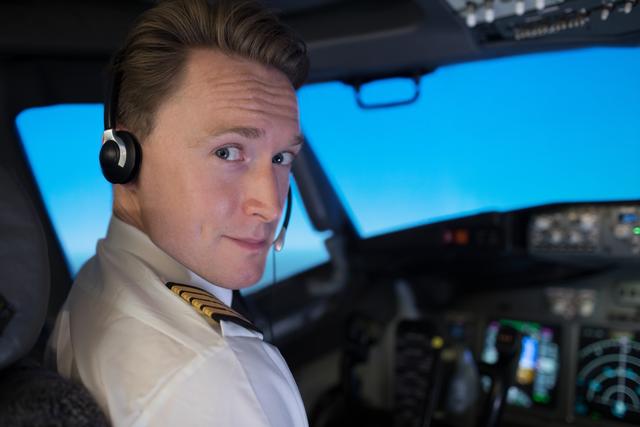Portrait of handsome young male pilot sitting in cockpit - Download Free Stock Photos Pikwizard.com
