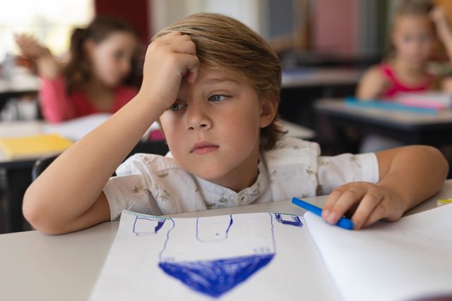 Sad schoolboy studying in classroom sitting at desks in school - Download Free Stock Photos Pikwizard.com
