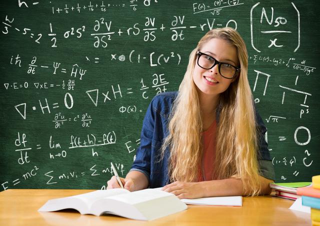 Portrait of woman sitting at desk in front of black board - Download Free Stock Photos Pikwizard.com
