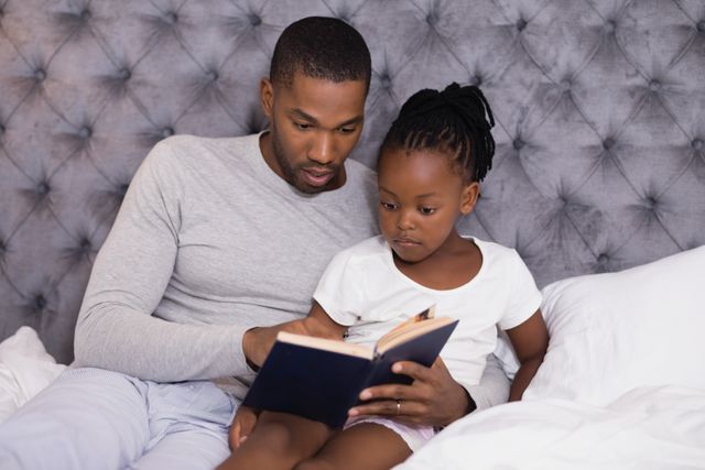 Man with daughter reading book on bed - Download Free Stock Photos Pikwizard.com
