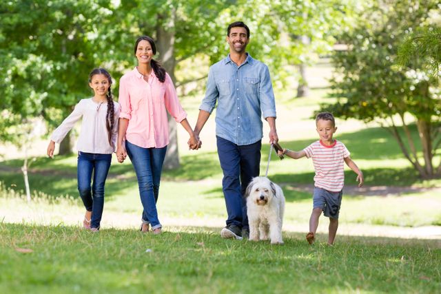 Portrait of happy family enjoying together with their pet dog in park