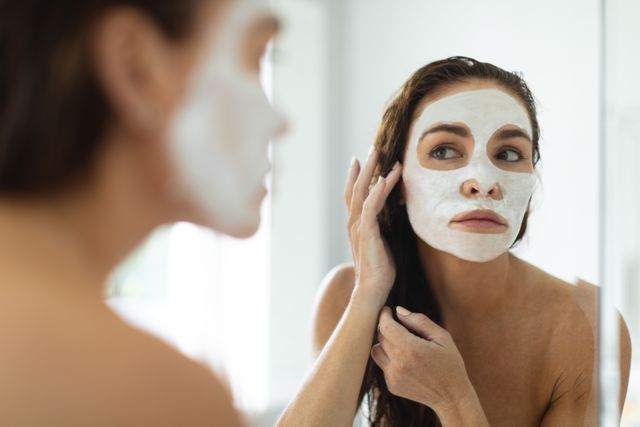 Woman with facial mask on her face looking in mirror - Download Free Stock Photos Pikwizard.com
