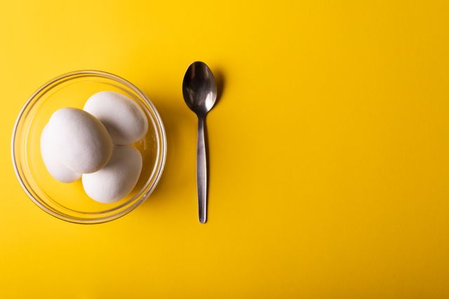 Overhead view of white eggs in bowl by spoon on yellow background with copy space - Download Free Stock Photos Pikwizard.com