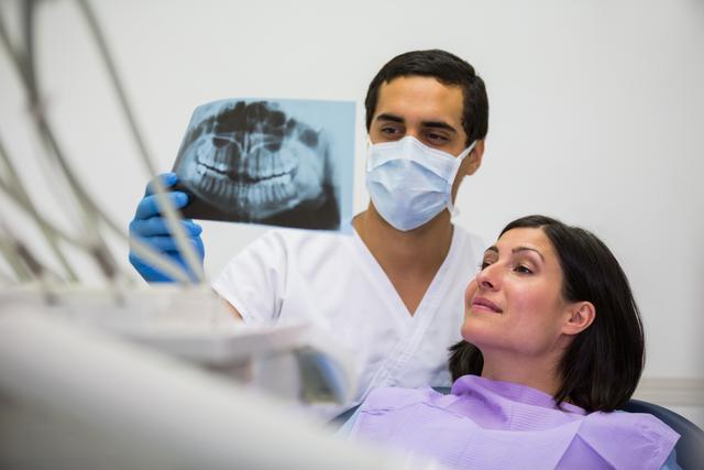 Young male dentist examining X-ray with the female patient - Download Free Stock Photos Pikwizard.com