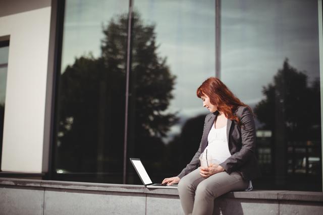 Pregnant businesswoman using laptop in office premises