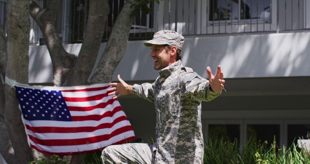 Caucasian son holding american flag hugging his military dad in uniform in the garden. veteran soldier returning home concept