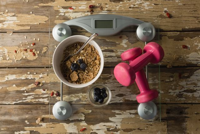 Bowl of breakfast and dumbbells on weighing scale - Download Free Stock Photos Pikwizard.com