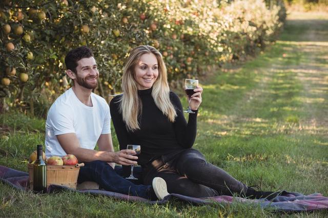 Couple having wine in apple orchard - Download Free Stock Photos Pikwizard.com