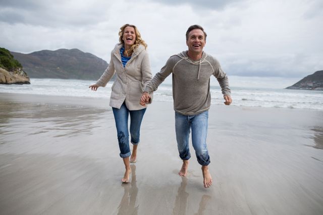 Mature couple running on the beach - Download Free Stock Photos Pikwizard.com