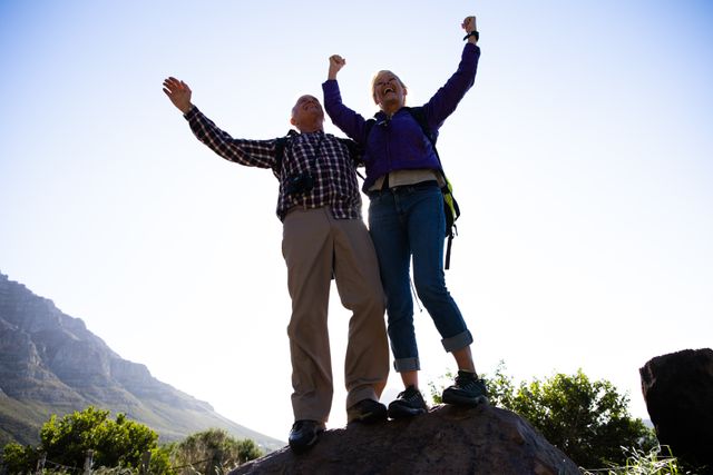 Low angle view of active senior couple holding hands up in a gesture of triumph - Download Free Stock Photos Pikwizard.com
