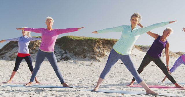 Diverse group of senior women doing yoga and stretching at beach. Retirement, friendship, healthy and active lifestyle.