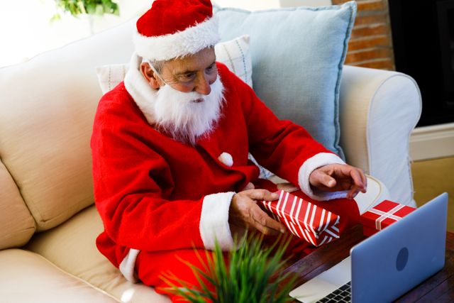 Top view of an old caucasian man wearing a santa clause costume holding out a christmas gift in fron - Download Free Stock Photos Pikwizard.com