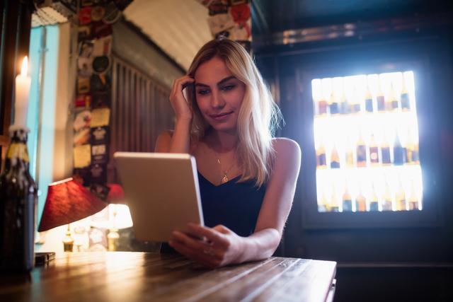 Beautiful smiling woman using digital tablet in bar