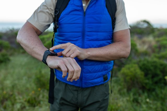 Mid section of caucasian hiker senior man using smartwatch while trekking in the mountains - Download Free Stock Photos Pikwizard.com