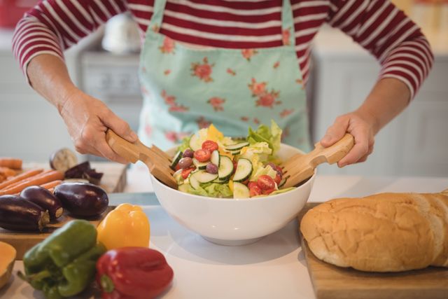 Senior woman mixing vegetables salad in kitchen - Download Free Stock Photos Pikwizard.com