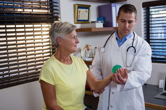 Physiotherapist assisting senior woman with stress ball exercise - Download Free Stock Photos Pikwizard.com