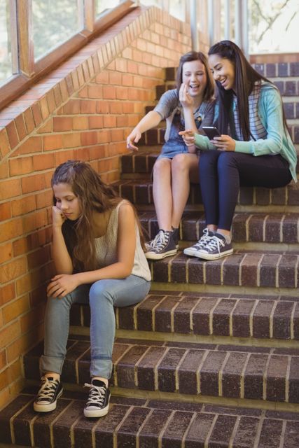 School friends bullying a sad girl in school corridor - Download Free Stock Photos Pikwizard.com