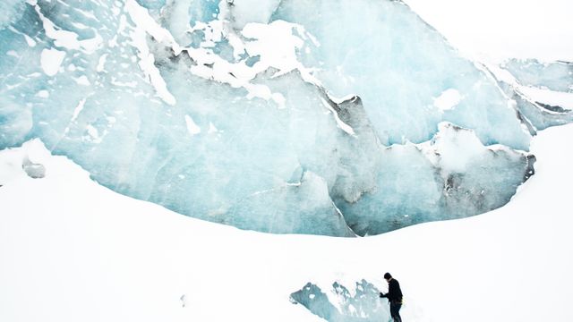 a person standing in front of a glacier - Download Free Stock Photos Pikwizard.com