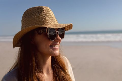 Woman in sunglasses and hat relaxing on the beach - Download Free Stock Photos Pikwizard.com