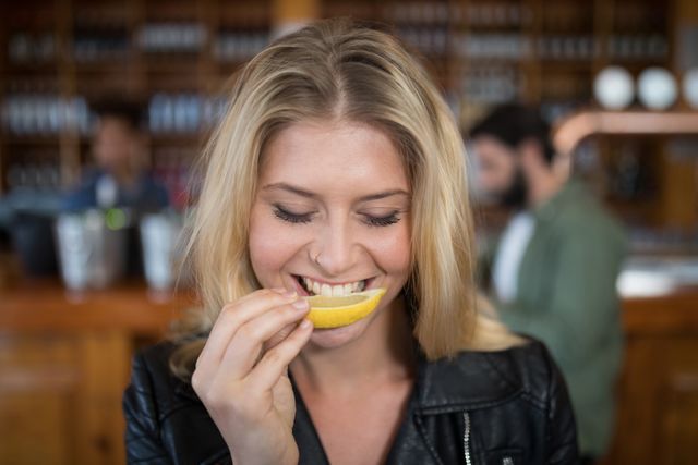 Beautiful woman biting into lemon wedge after having tequila shot - Download Free Stock Photos Pikwizard.com
