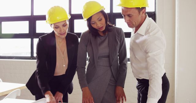 A multicultural team of construction professionals discusses plans intently. - Download Free Stock Photos Pikwizard.com