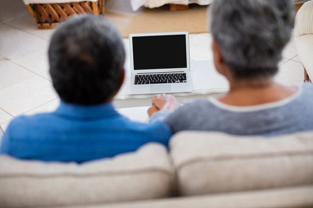 Senior couple holding hands while looking at the laptop - Download Free Stock Photos Pikwizard.com