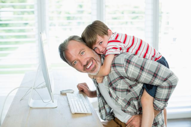 Playful father and son working on computer at home - Download Free Stock Photos Pikwizard.com