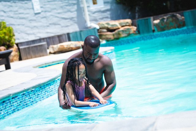 African american father helping daughter swimming in pool on sunny day - Download Free Stock Photos Pikwizard.com