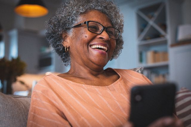 Happy african american senior woman in living room using smartphone smiling - Download Free Stock Photos Pikwizard.com