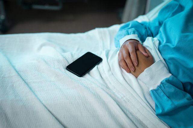 Mixed race female patient lying on hospital bed with smartphone - Download Free Stock Photos Pikwizard.com