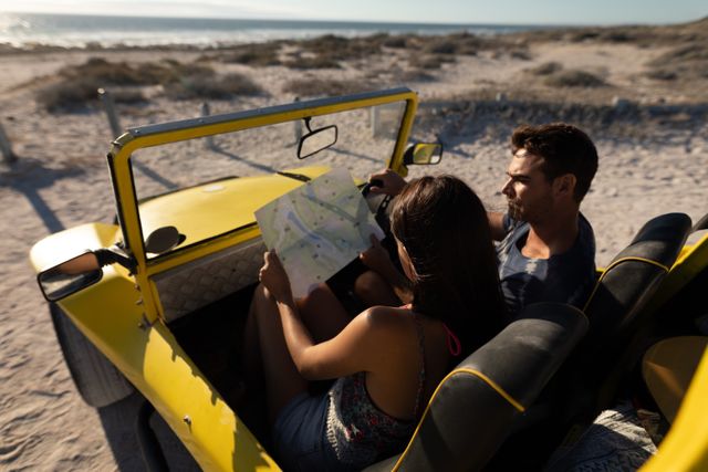 Caucasian couple sitting in beach buggy at sunny beach, looking at map and talking - Download Free Stock Photos Pikwizard.com