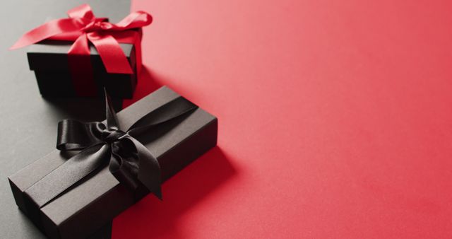 Two black gift boxes with red and black ribbons on black and red background with copy space - Download Free Stock Photos Pikwizard.com