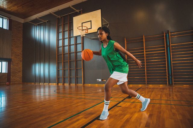 Mixed race female basketball player practicing dribbling ball in court - Download Free Stock Photos Pikwizard.com