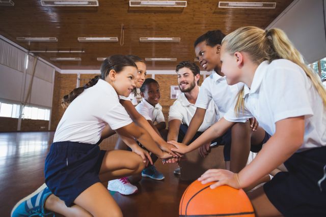 Sports teacher and school kids forming hand stack in basketball court - Download Free Stock Photos Pikwizard.com