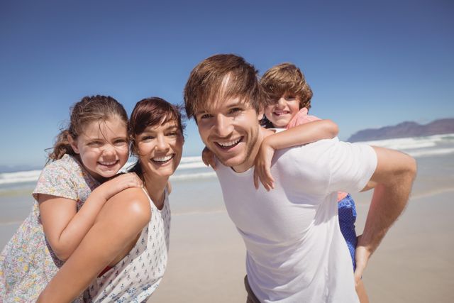 Portrait of family smiling together at beach against clear blue sky
