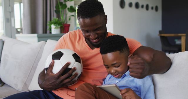 African american father and son cheering together while watching sports on digital tablet at home - Download Free Stock Photos Pikwizard.com