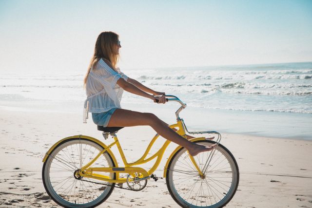 Caucasian woman relaxing on beach riding bicycle in the sand. summer beach vacation by the sea.