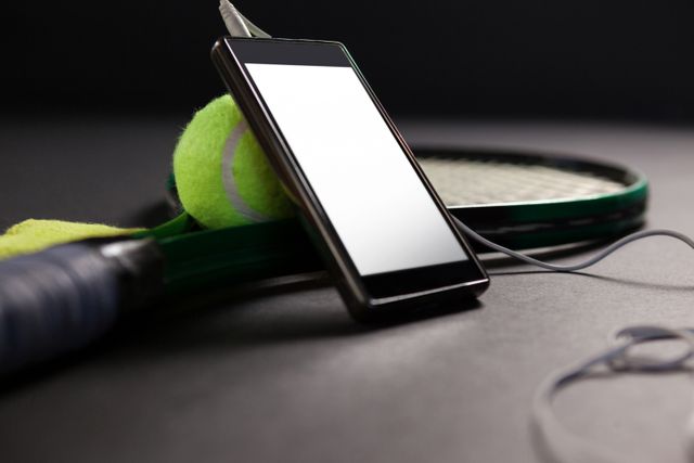 Close up of mobile phone and headphones by tennis ball with racket - Download Free Stock Photos Pikwizard.com
