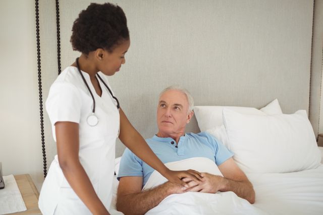 Nurse interacting with senior man on bed - Download Free Stock Photos Pikwizard.com