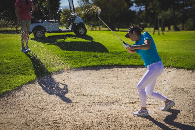 Caucasian woman hitting golf ball out of sand trap at golf course - Download Free Stock Photos Pikwizard.com