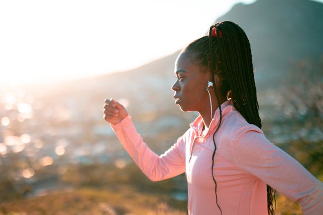 Fit african american woman exercising in countryside, wearing wireless earphones - Download Free Stock Photos Pikwizard.com
