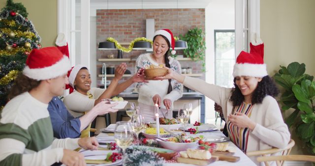 Happy group of diverse friends in santa hats celebrating meal at christmas time. christmas festivities, celebrating at home with friends.
