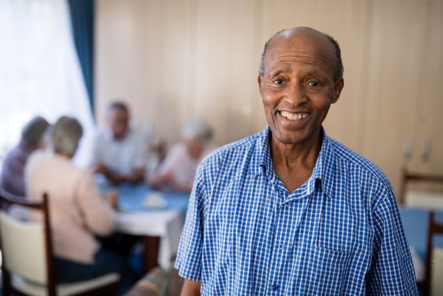 Portrait of smiling senior man standing against friends at nursing home