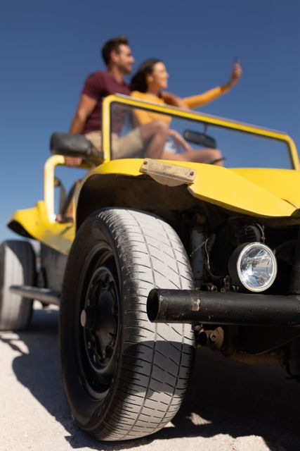 Happy caucasian couple sitting on beach buggy in the sun taking selfie, focus on foreground - Download Free Stock Photos Pikwizard.com