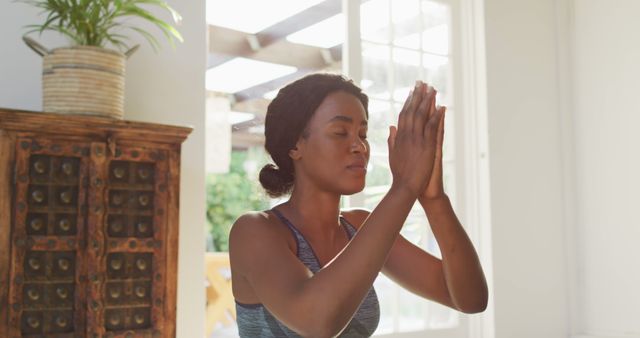 Image of relaxed african american woman practicing yoga at home. active healthy lifestyle, exercising at home.