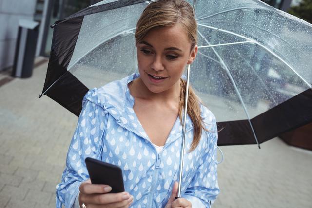 Beautiful woman holding umbrella while using mobile phone - Download Free Stock Photos Pikwizard.com