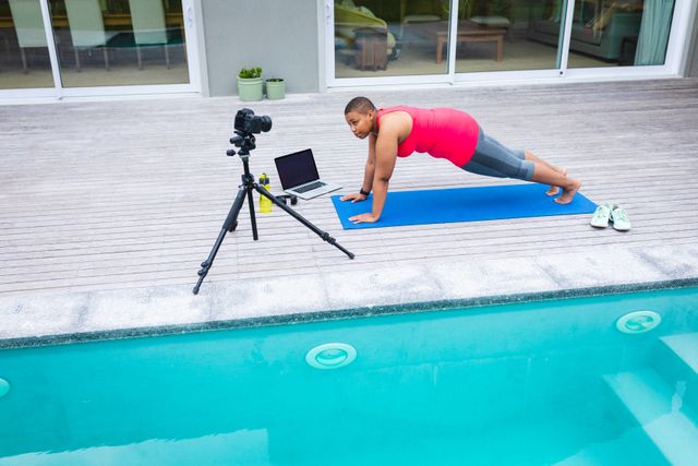 African american female blogger recording a video on digital camera while exercising by the pool - Download Free Stock Photos Pikwizard.com